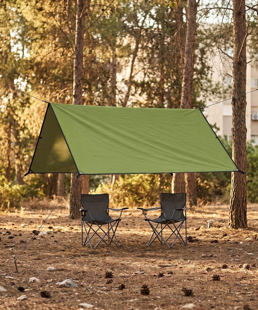 יריעת צל VELA 210 מתוחה בין עצים מעל כיסאות קמפינג ביער